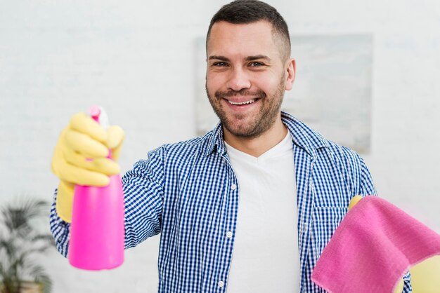 Homem sorridente posando com pano e produto de limpeza