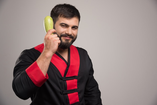 Homem sorridente segurando abobrinha fresca na mão.