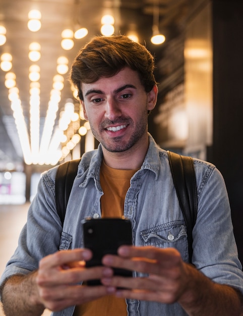 Homem sorridente segurando e olhando para celular