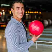 Foto grátis homem sorridente segurando uma bola de boliche vermelha tiro médio
