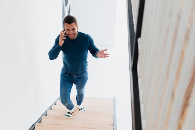 Homem sorridente subindo escadas e falando no telefone