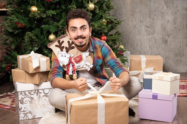 Homem sorridente, tentando abrir seus presentes.