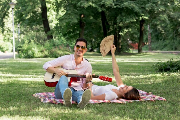 Homem sorridente tocando violão no parque