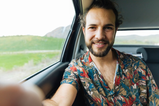 Homem sorridente tomando selfie no carro