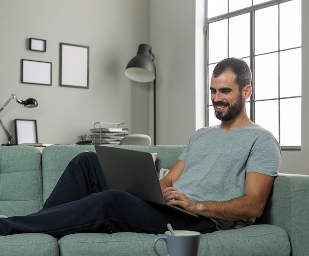 Homem sorridente trabalhando em casa em um laptop