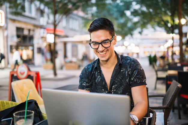 Homem sorridente trabalhando no laptop no café