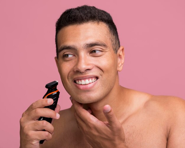 Homem sorridente usando um barbeador elétrico