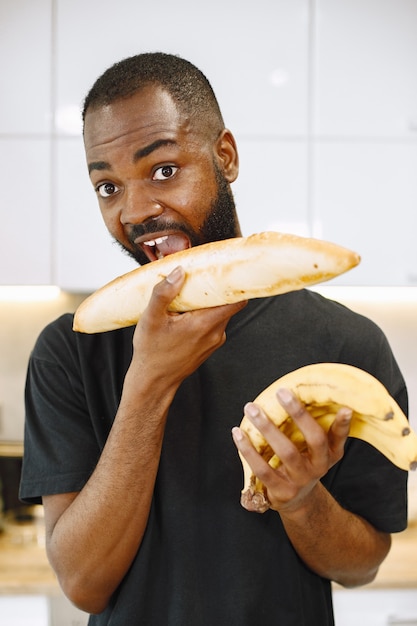 Homem sorrindo enquanto segura o pão como se estivesse mordendo