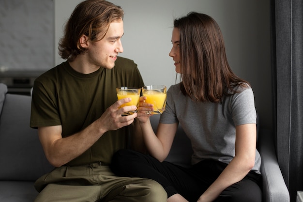 Homem sorrindo para a namorada enquanto segura o copo de suco de laranja