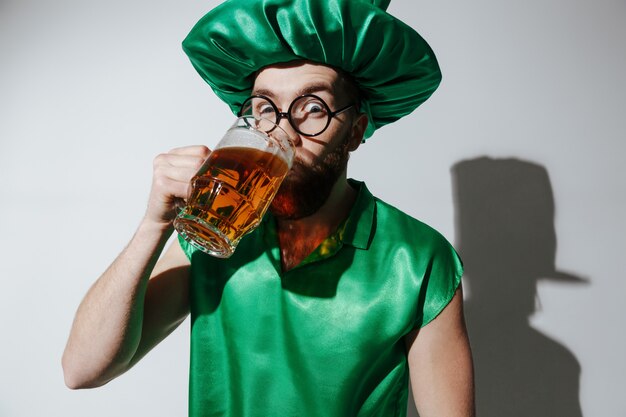 Homem surpreendido em traje de st.patriks, bebendo cerveja