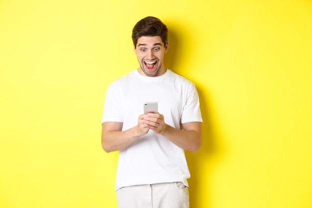 Homem surpreso lendo mensagem de texto no celular, parecendo surpreso e feliz na tela do smartphone