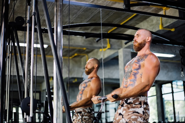 Homem tatuado fazendo exercícios na academia