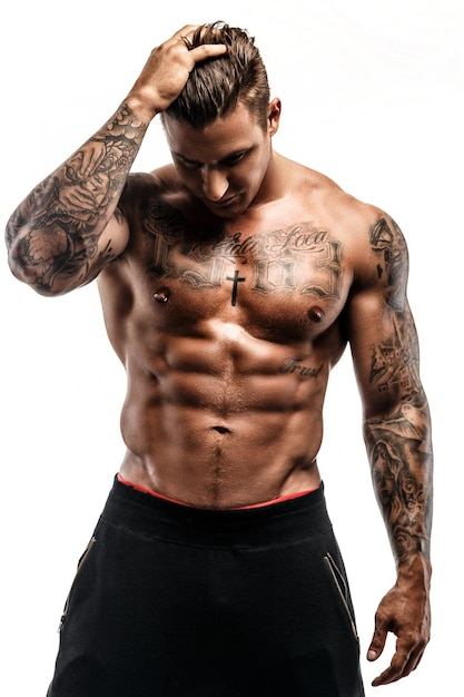 Homem tatuado muscular sem camisa isolado no fundo branco.