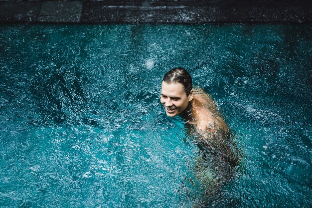 homem tatuado na piscina na chuva.