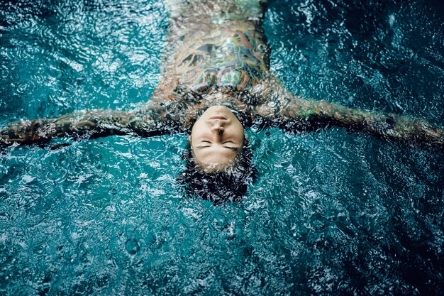 homem tatuado na piscina na chuva.