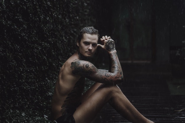 homem tatuado posando na chuva