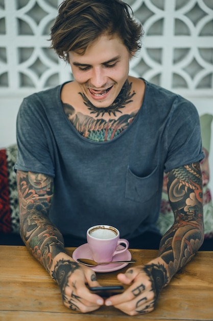 Foto grátis homem tatuado tomando café em um café