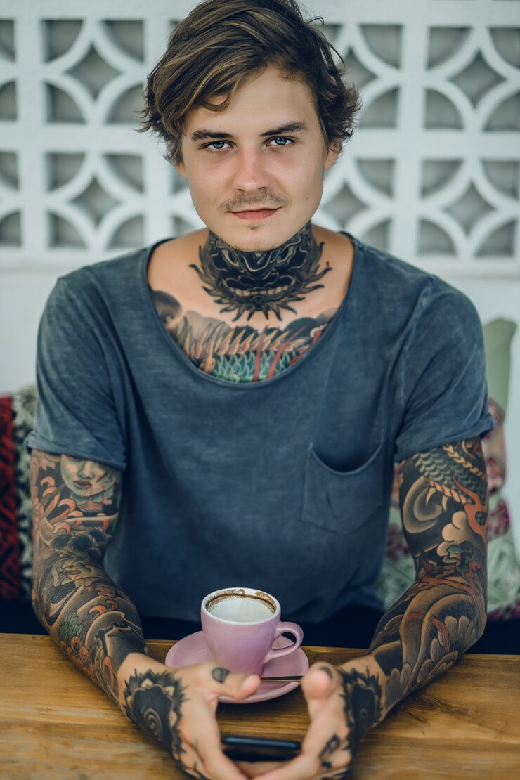 Foto grátis homem tatuado tomando café em um café