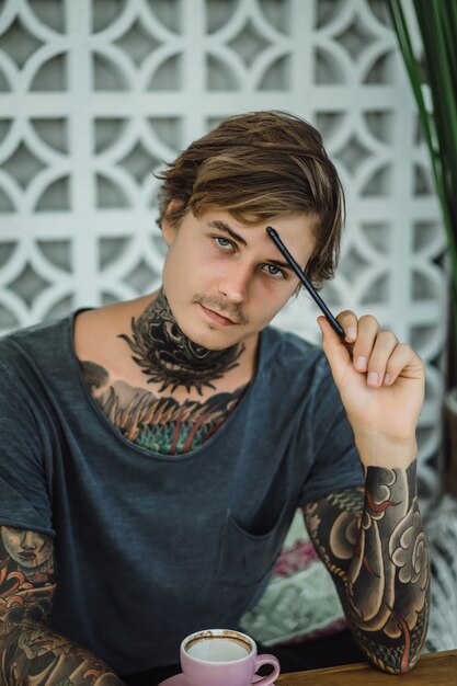 Foto grátis homem tatuado tomando café em um café