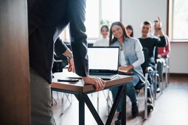 Homem tem uma pergunta. mão levantada. grupo de pessoas em conferência de negócios em sala de aula moderna durante o dia