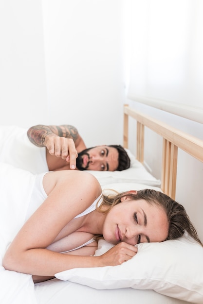 Foto grátis homem tentando acordar sua esposa deitada na cama