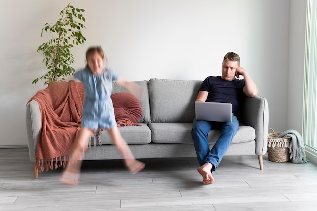 Foto grátis homem tentando trabalhar em um laptop de casa enquanto os filhos dela estão correndo