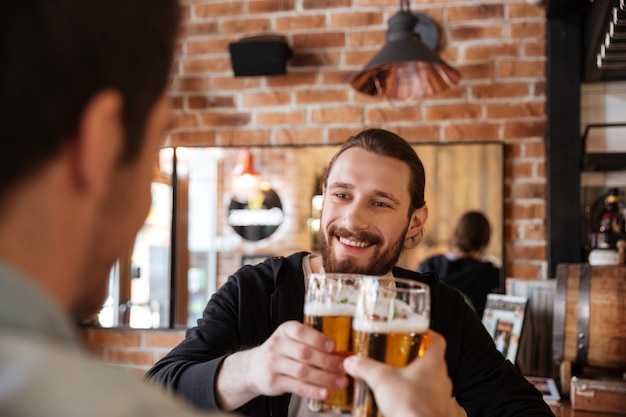 Foto grátis homem tilintar de copos com amigo no bar