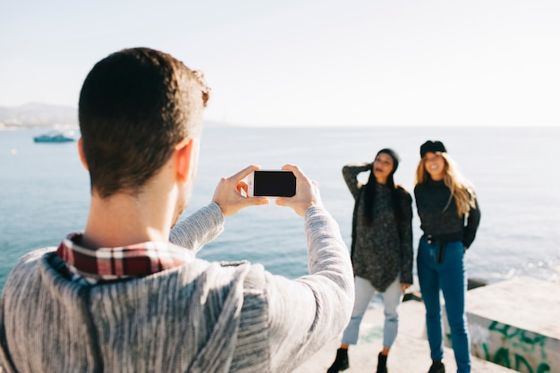 Homem tirando foto de meninas na frente do mar
