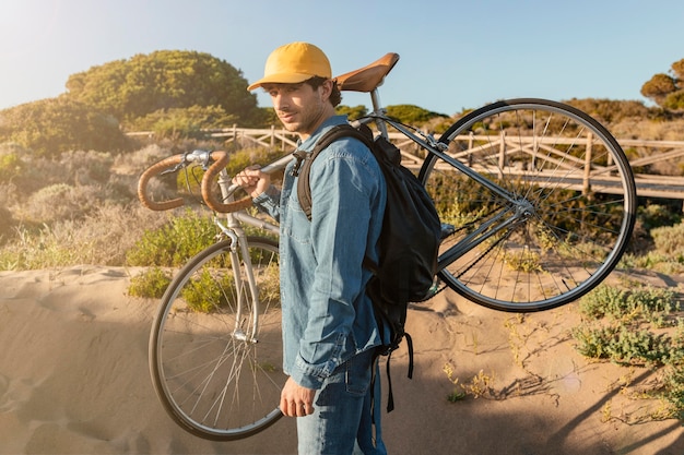 Foto grátis homem tiro médio carregando bicicleta