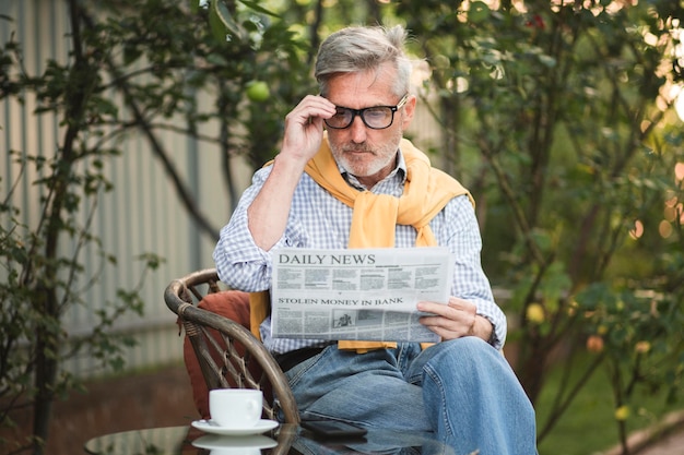 Homem tiro médio lendo jornal lá fora