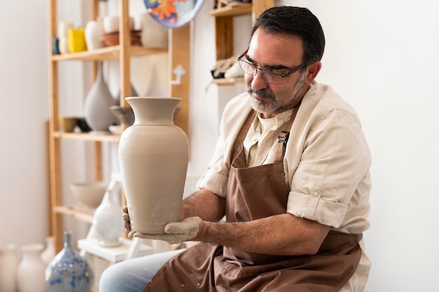 Foto grátis homem tiro médio segurando um vaso