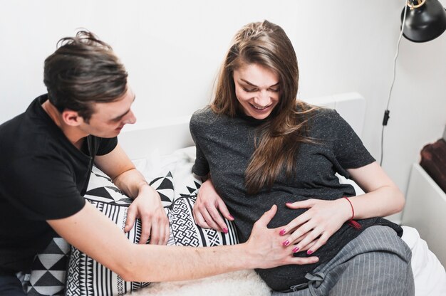 Homem tocando a barriga da mulher grávida no quarto