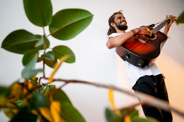 Homem tocando guitarra dentro de casa com espaço de cópia