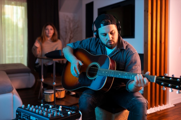 Homem tocando guitarra em casa vista frontal