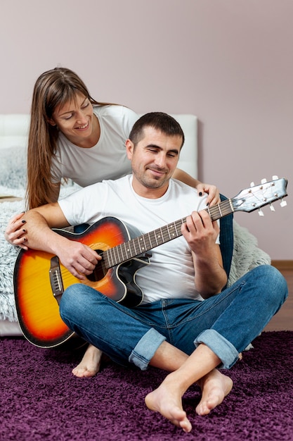 Homem tocando violão, assistido por sua namorada