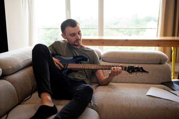 Homem tocando violão em casa