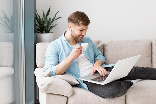 Homem tomando café e usando o laptop