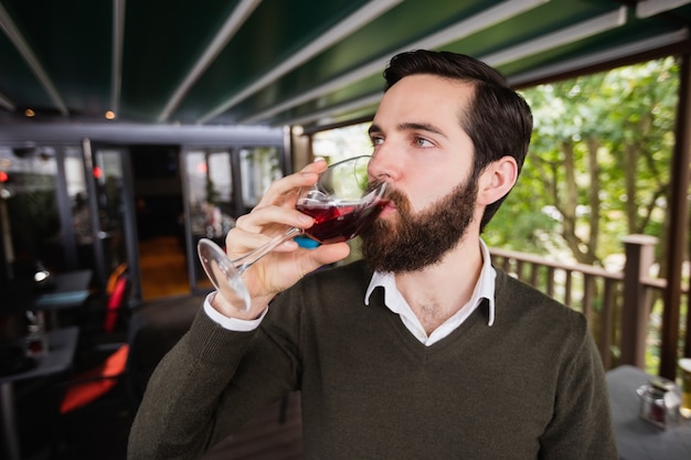 Homem tomando um copo de vinho no bar