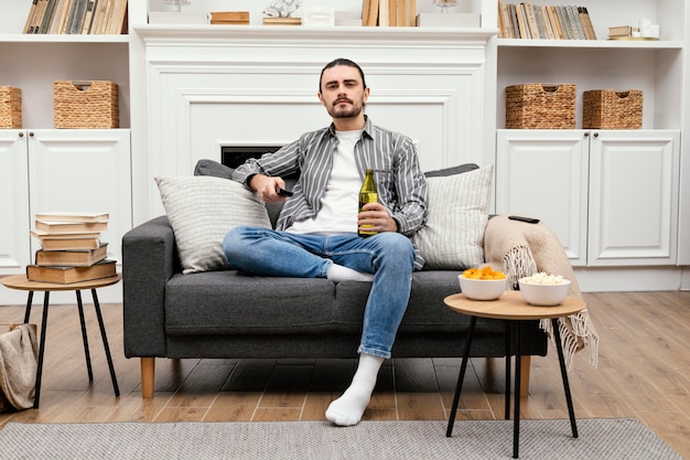 Homem tomando uma cerveja e assistindo tv dentro de casa