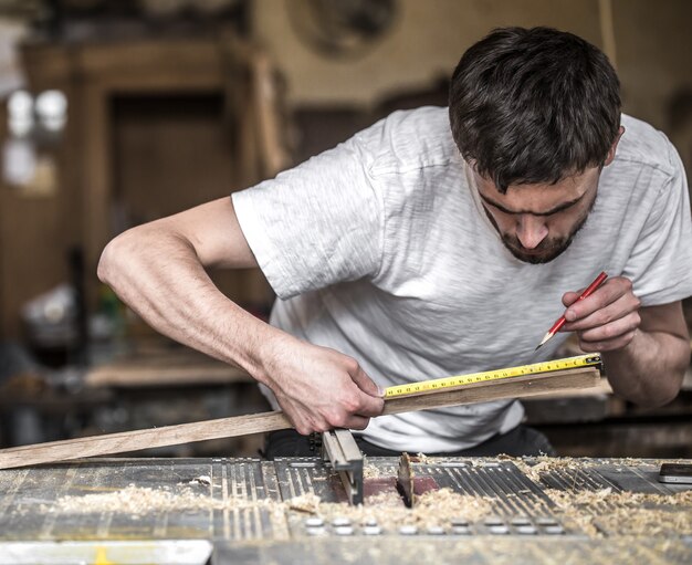 Homem trabalhando com produto de madeira na máquina