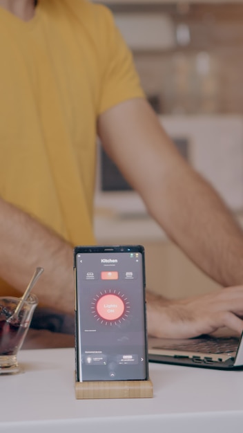 Foto grátis homem trabalhando em casa com sistema de iluminação de automação usando controle de voz no smartphone, desligando ...