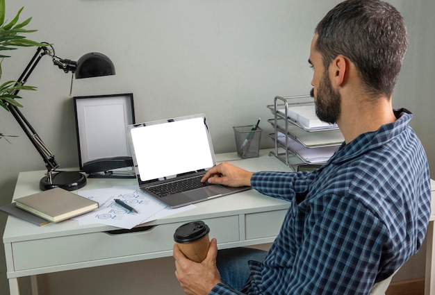 Homem trabalhando em casa enquanto toma café