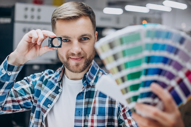 Homem trabalhando em uma gráfica com papel e tintas