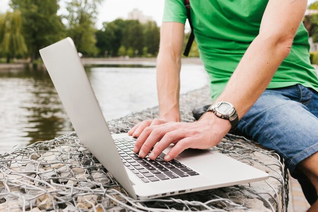 Homem trabalhando no laptop à beira do lago