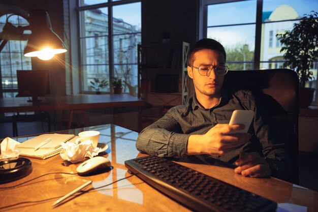 Homem trabalhando sozinho no escritório, ficando até tarde da noite.