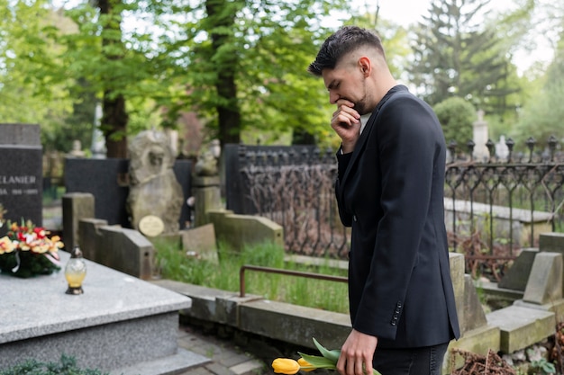 Foto grátis homem trazendo tulipas para um túmulo