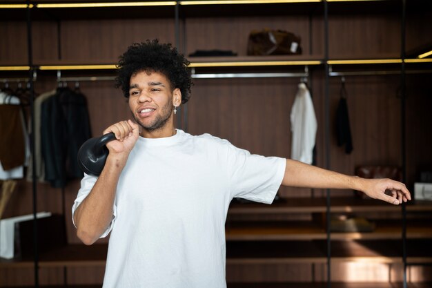 Homem treinando com kettlebell no armário plano médio