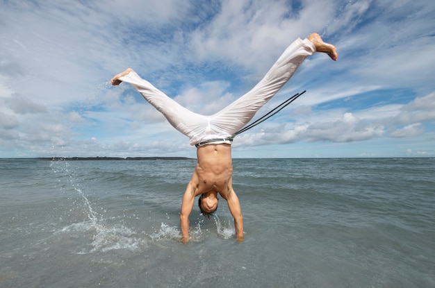 Foto grátis homem treinando para capoeira na praia