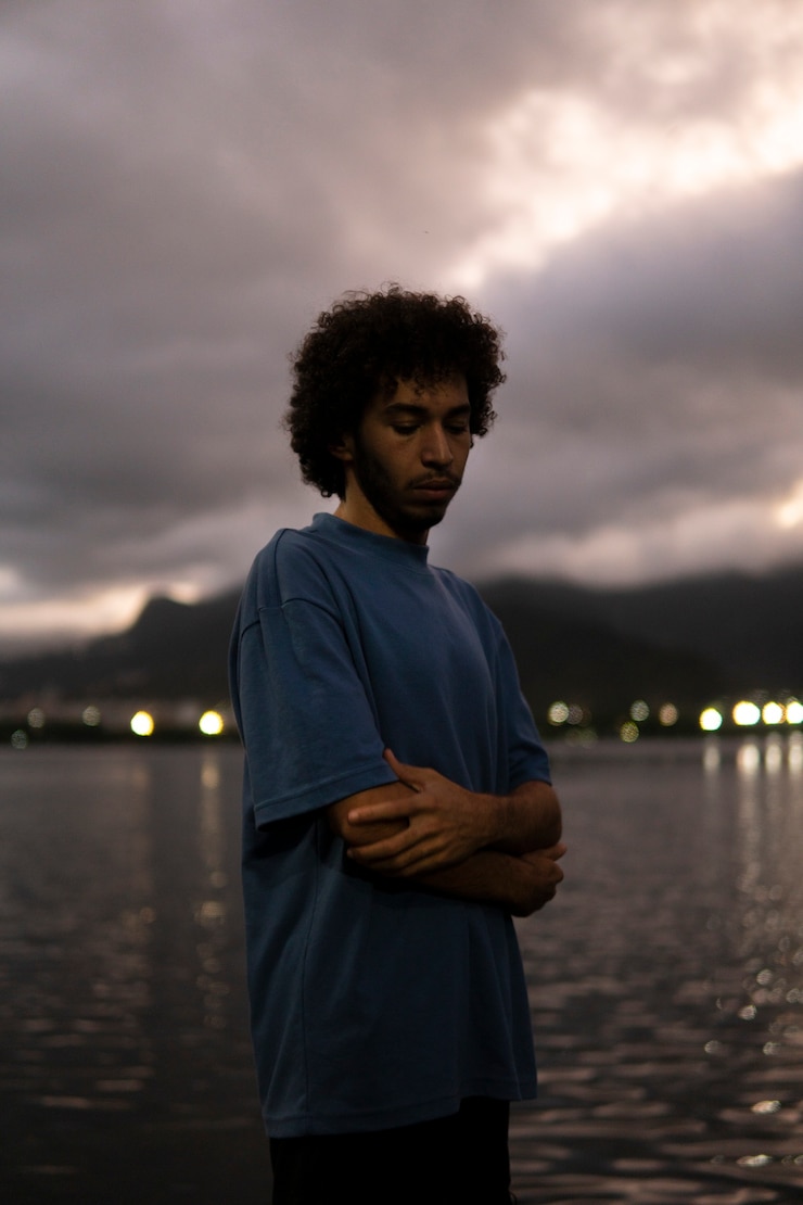 Foto grátis homem triste e contemplativo sentado à beira do lago