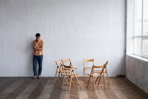 Homem triste sentado contra a parede em uma sessão de terapia de grupo